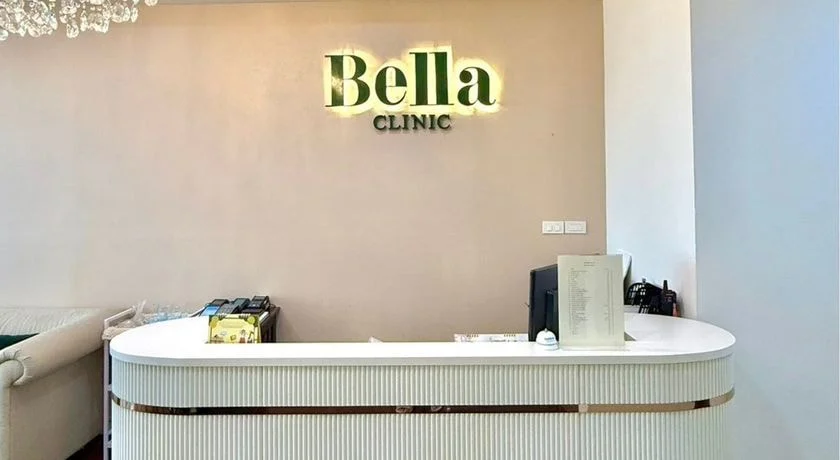ป้าย Bella Clinic เรืองแสงเหนือเคาน์เตอร์ต้อนรับสีขาวลายร่องขอบทอง